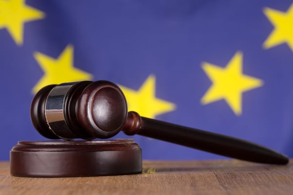 Gavel resting on sound block with european union flag in background